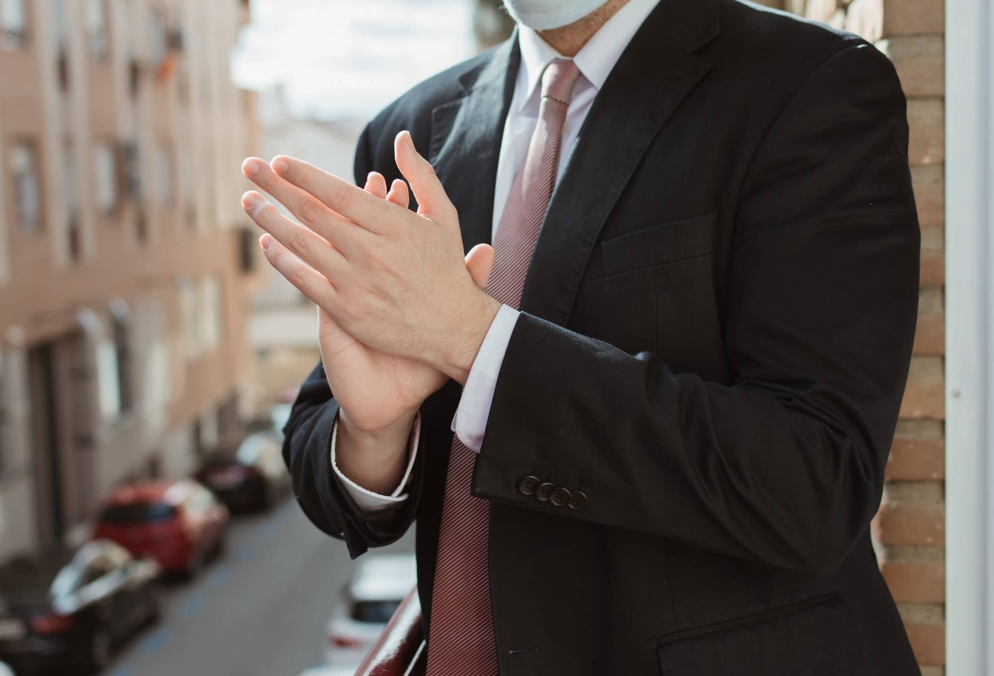 Business man with suit, tie and mask applauding people who are fighting against coronavirus